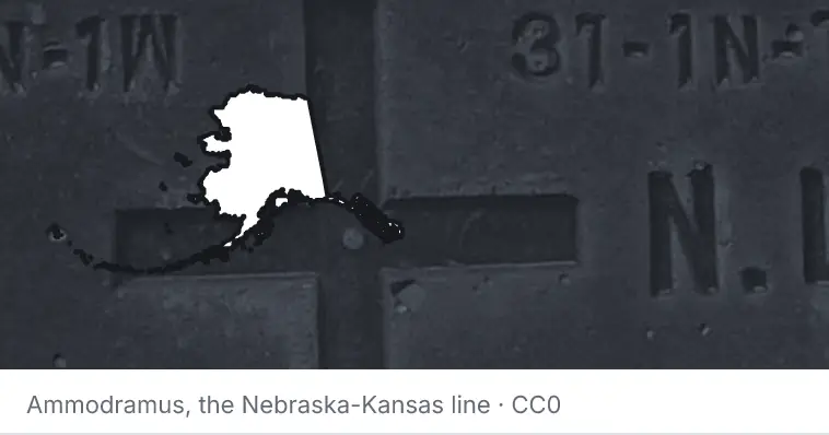 A survey monument's crosshair, under the outline of Alaska. The source names the Nebraska-Kansas line.