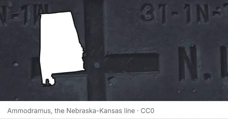 A survey monument's crosshair, under the outline of Alabama. The source names the Nebraska-Kansas line.