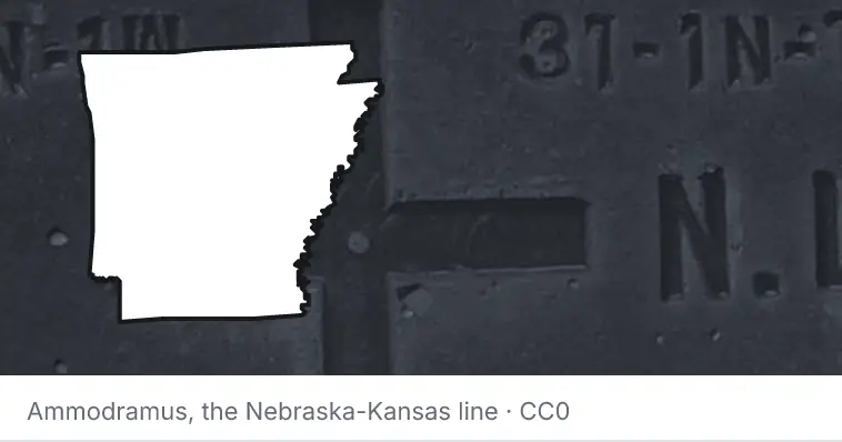 A survey monument's crosshair, under the outline of Arkansas. The source names the Nebraska-Kansas line.