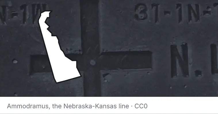 A survey monument's crosshair, under the outline of Delaware. The source names the Nebraska-Kansas line.