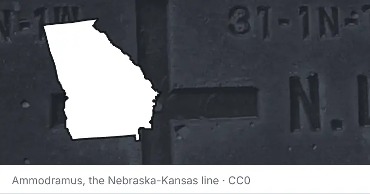 A survey monument's crosshair, under the outline of Georgia. The source names the Nebraska-Kansas line.