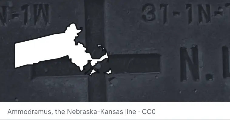 A survey monument's crosshair, under the outline of Massachusetts. The source names the Nebraska-Kansas line.