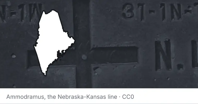 A survey monument's crosshair, under the outline of Maine. The source names the Nebraska-Kansas line.