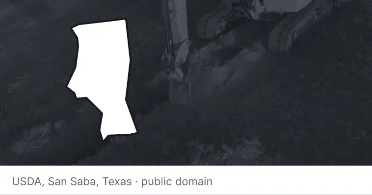 An excavator cutting a trench, under the outline of Iredell County. The source names San Saba, Texas.
