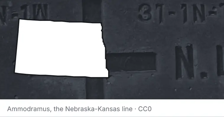 A survey monument's crosshair, under the outline of North Dakota. The source names the Nebraska-Kansas line.