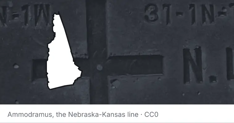 A survey monument's crosshair, under the outline of New Hampshire. The source names the Nebraska-Kansas line.