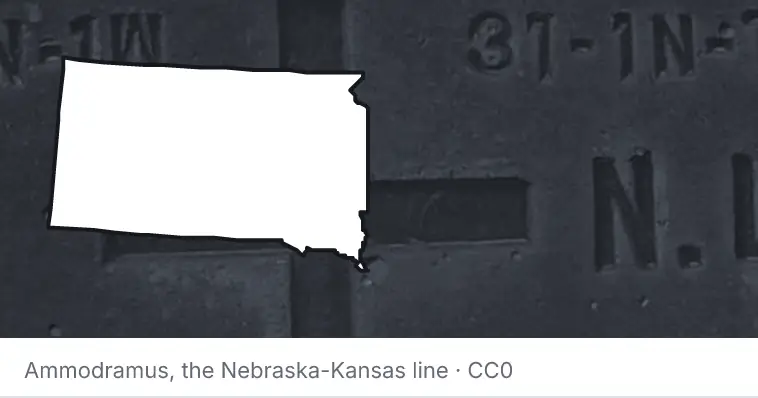A survey monument's crosshair, under the outline of South Dakota. The source names the Nebraska-Kansas line.