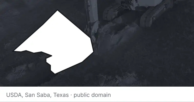 An excavator cutting a trench, under the outline of Comal County. The source names San Saba, Texas.