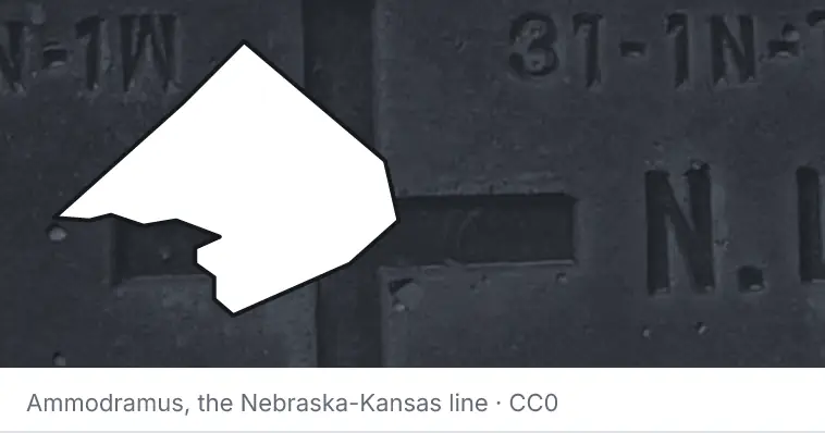 A survey monument's crosshair, under the outline of Comal County. The source names the Nebraska-Kansas line.