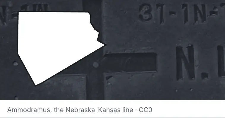 A survey monument's crosshair, under the outline of Ellis County. The source names the Nebraska-Kansas line.