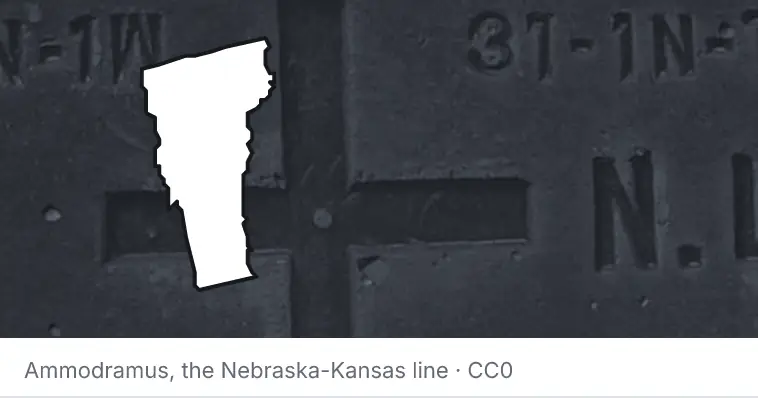 A survey monument's crosshair, under the outline of Vermont. The source names the Nebraska-Kansas line.