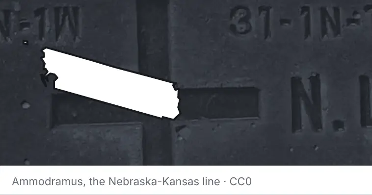 A survey monument's crosshair, under the outline of Whatcom County. The source names the Nebraska-Kansas line.