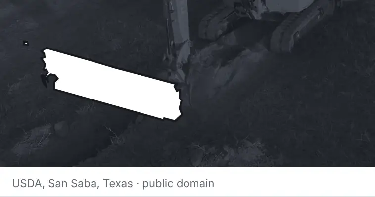 An excavator cutting a trench, under the outline of Whatcom County. The source names San Saba, Texas.