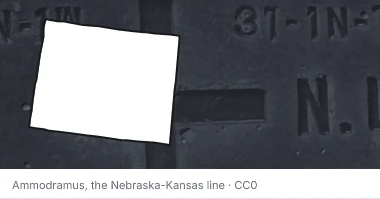 A survey monument's crosshair, under the outline of Wyoming. The source names the Nebraska-Kansas line.